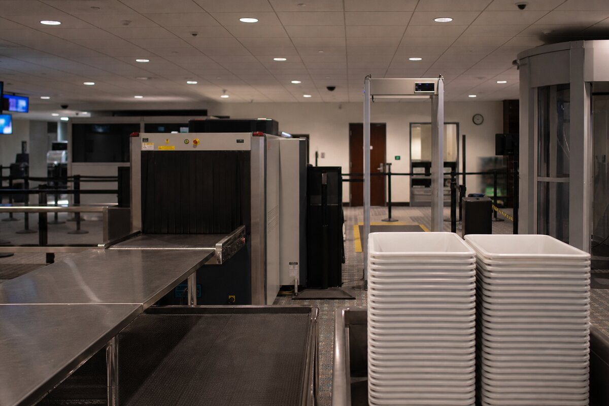 Airport security screening lane with X-ray and checkpoint equipment, no people