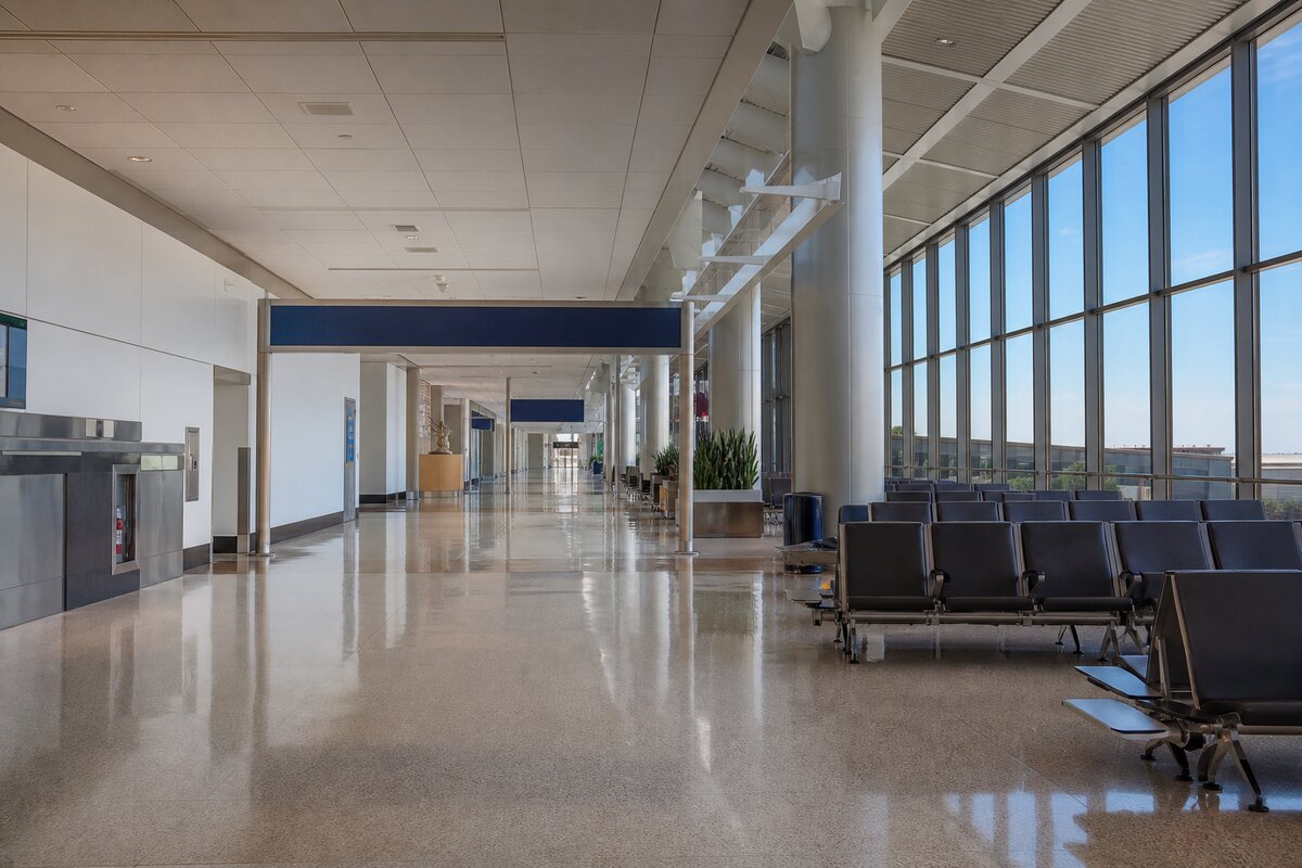 Empty airport terminal concourse with seating, signage, and facilities equipment