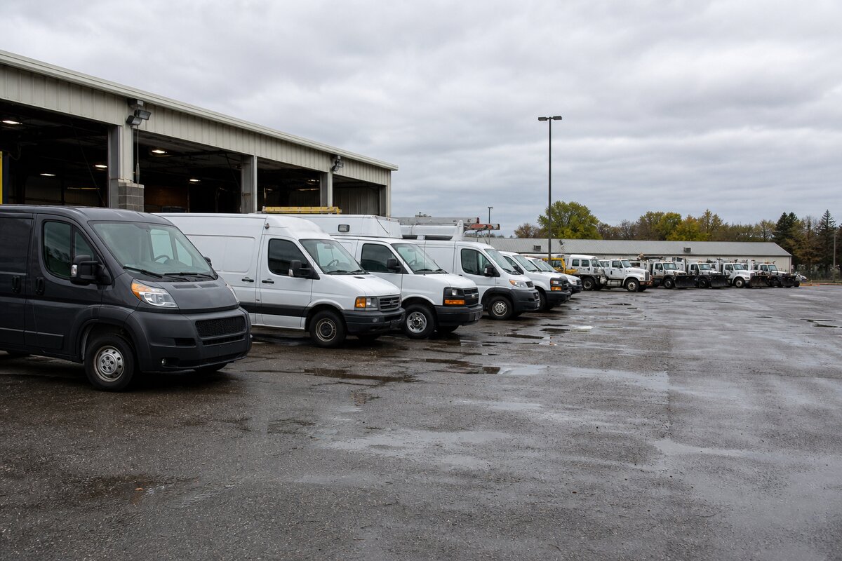 Public fleet vehicles parked in a municipal depot yard beside maintenance bays