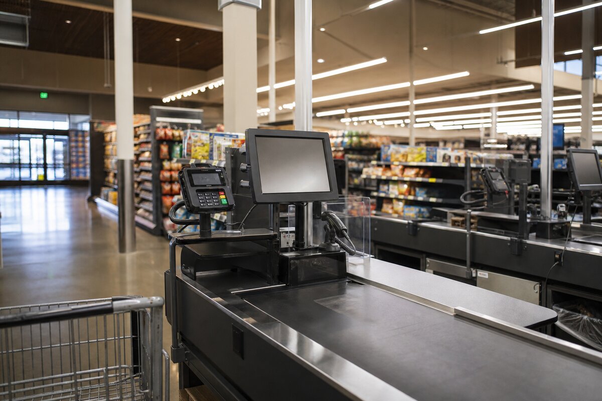 Empty retail checkout lane with POS terminals and payment equipment on a store floor
